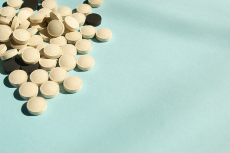 Lots of pills in the corner of the photo. white and black tablets are mixed together. Different tablets on a blue background. A handful of pills in isolation.の写真素材