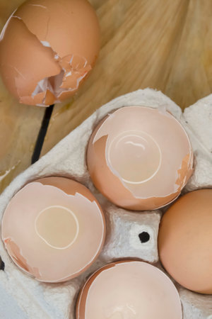In the egg tray are halves of the shell. Egg waste is the shell in the tray. ON the wooden table is a tray with an empty eggshell.の写真素材