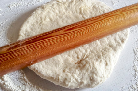 rolling pin on the test. Giving the dough the desired shape. Roll out the dough on the pizza. Baking - dough preparation.の写真素材