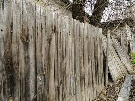 The old fence is falling apart. A fence in a village made of wood is falling. a bad, dangerous hedge. The wooden fence falls.の写真素材
