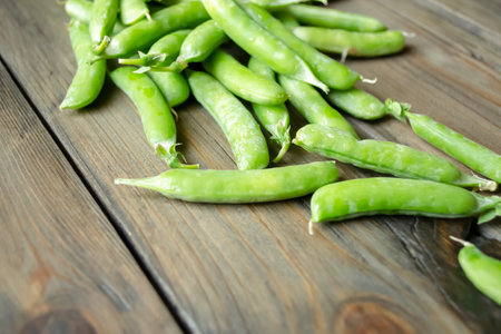 Green peas in pods lie on a wooden board. Useful legumes. lots of green pea pods. Harvest green peas in pods.の写真素材