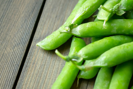 Green peas in pods lie on a wooden board. Useful legumes. lots of green pea pods. Harvest green peas in pods.の写真素材