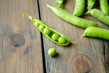 Green peas on a wooden table. Beans in a pod. green beans in an open knock on the table. Lots of green pea pods.の写真素材