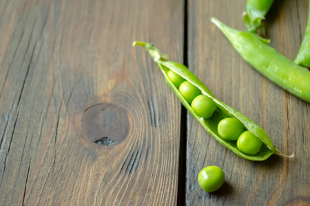 Green peas on a wooden table. Beans in a pod. green beans in an open knock on the table. Lots of green pea pods.の写真素材