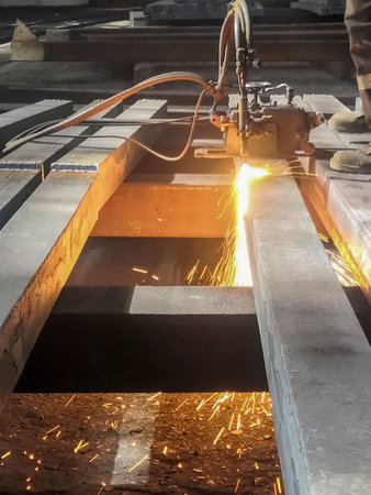 Metallurgical plant - metal processing. Cutting a square before processing and sorting. Steel production at the plant. The workpiece is processed by a gas-cutting machine.の写真素材