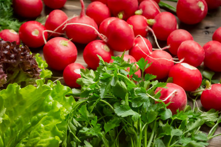 Spring gifts of nature - useful vegetables for salad. Radishes, lettuce, parsley, dill on a wooden table. Bright colors of spring vegetables and greens,の写真素材