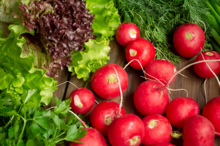 Spring gifts of nature - useful vegetables for salad. Radishes, lettuce, parsley, dill on a wooden table. Bright colors of spring vegetables and greens,の写真素材