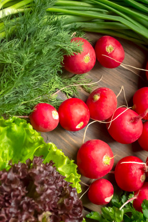 Radishes, lettuce, parsley, dill and onions on a wooden table. Spring gifts of nature - useful vegetables for salad. Bright colors of spring vegetables and greens,の写真素材