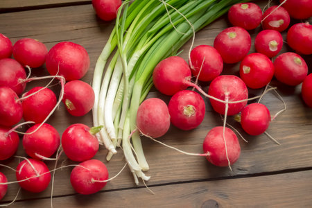 Radish lies next to green onions on a wooden table. Spring vegetables for salad. Useful crops in early spring. Seasonal vegetables in spring.の写真素材