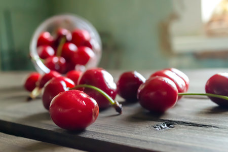 Fresh cherries in a glass. On a wooden table is a glass of cherry. Cherries spilled out of the glass onto the table.の写真素材