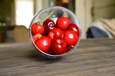 Red cherries in a glass. A glass glass of cherry lies on a wooden table. Summer berries in a glass are healthy fresh.の写真素材