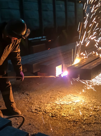 An employee of the plant processes metal. metallurgy. Work at a foundry metallurgical plant. Processing of finished metal for further shipment. The process of cutting metal with a gas machine.の写真素材