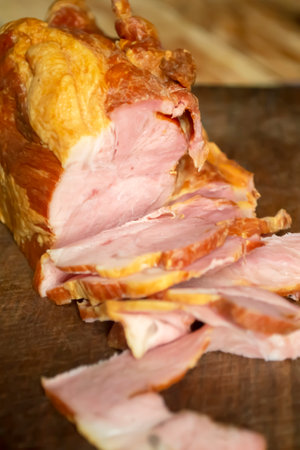 Pork slicing. A piece of smoked balyk on a wooden board. Smoked pork belly in section.の写真素材