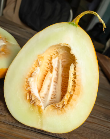 Melon halves with pits. Unpeeled melon on a wooden table. Ripe, honey melon with seeds in the section.の写真素材