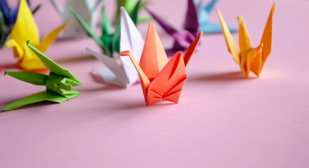 Paper cranes - origami on a pink background. On the table are colored cranes made of paper. cranes on desires. Beautiful paper cranes. Do-it-yourself jewelry.の写真素材