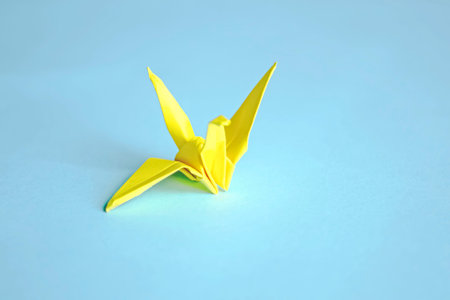 Yellow paper crane on a blue background. On a blue background there is one paper crane. Origami, Japanese culture is a crane.の写真素材