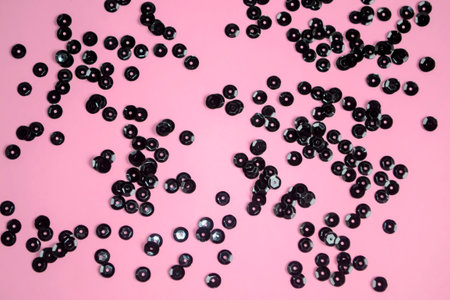 Black sequins on a pink background. Pink background with black decorations. black circles are scattered on pink.の写真素材