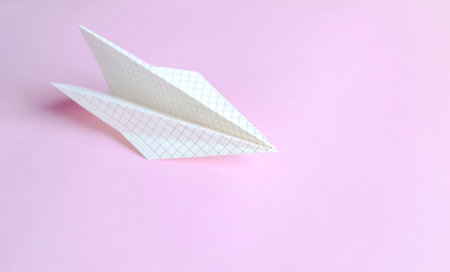 The symbol of freedom and creative flight is a paper plane on pink. Paper airplane made of paper in a cage on a pink background.の写真素材