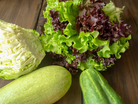 Young cabbage, zucchini, lettuce, cucumber on a wooden table. Green vegetables for salad in the spring. useful crops for health.の写真素材