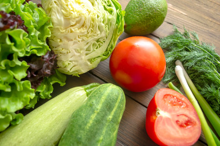 On a wooden table are healthy vegetables. Tomatoes, cabbage, zucchini, cucumbers and avocado for salad. green and red vegetables for health.の写真素材