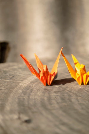 Origami - paper cranes for the fulfillment of desires. Red and orange paper cranes stand on a wooden deck.の写真素材