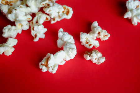 Popcorn is scattered on a red background. There is a lot of light popcorn on the red table. The appetizer for the movie is popcorn.の写真素材