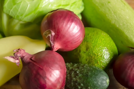 Red onion next to green vegetables. Red onion, zucchini, cabbage, cucumber and avocado on a wooden table. Vegetables in the spring.の写真素材
