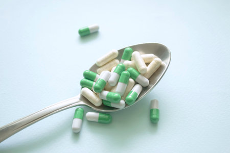 On a blue background lies a spoon filled with tablets and capsules. Traditional medicine - a lot of medicinal capsules and tablets in a metal spoon. The benefits and harms of tablets.の写真素材