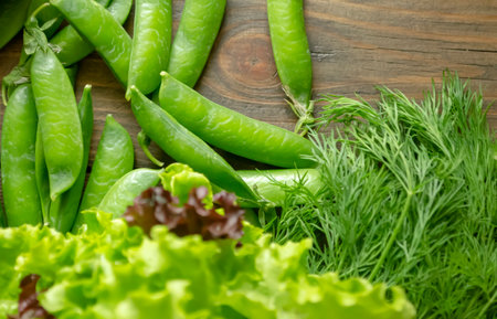 On a wooden table, a close-up of green vegetables and herbs is shot. Spring vegetables and herbs for vegetarians. green healthy food.の写真素材