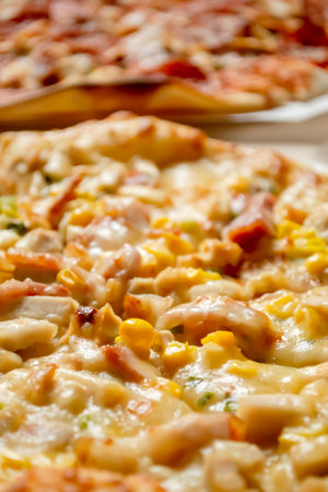 Cheese pizza with corn next to meat pizza. Two pizzas are lying side by side. vertical photo.の写真素材