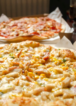 Cheese pizza with corn next to meat pizza. Two pizzas are lying side by side. vertical photo.の写真素材