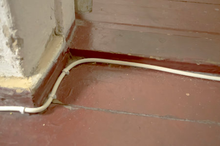 The cable is nailed to the floor. An electrical cable is laid on the floor in the house.の写真素材