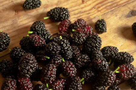 Mulberries on a wooden table. Useful summer berries. Lots of black mulberries on a wooden table.の写真素材