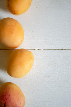 Apricots lie in a row on a wooden table. Ripe apricots on the table. A row of apricots on a white tree.の写真素材