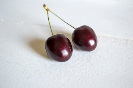 Two cherries with a common tail on a white background. close-up of dark cherry on a white...