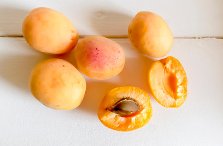 Fresh apricots on a wooden table. Summer fruits are juicy apricots. Orange large apricots on a white table.の写真素材