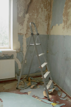 Renovation in the room, among the tattered wallpaper there is a staircase. stairs for renovation in a dirty room.の写真素材