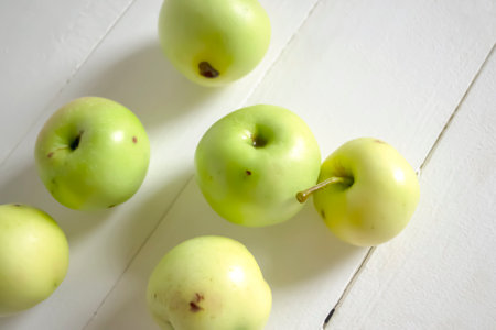 Wormy apples lie on a white table. Fallen apples with diseases on the table. Harvest of sick apples....
