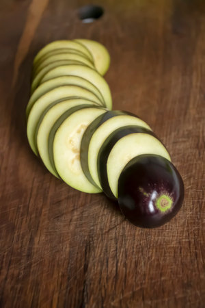 Eggplant sliced into rings on a wooden table. Smooth circles of eggplant laid out in a row. Slicing eggplant.の写真素材