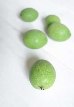 Green walnut fruits on a white background. On a wooden white table are walnut fruits.の写真素材