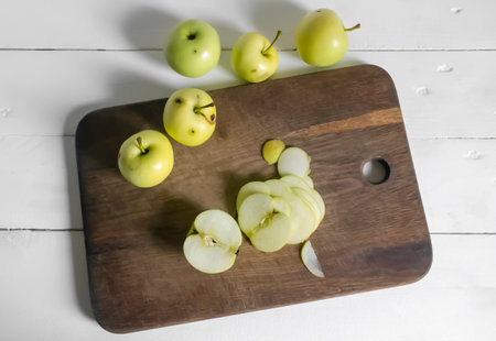 Processing of wormy apples. Spoiled apples with black dots - crop processing. Slicing an apple on a wooden board.の写真素材