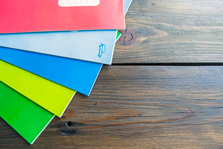 On a wooden table are several thin notebooks for school. Colored notebooks for school.の写真素材