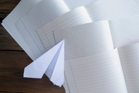 Self-made of paper on open school notebooks. On the open notebooks is a paper plane.の写真素材
