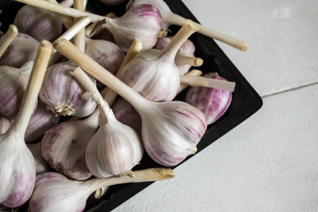 young garlic in a box on a white table. Garlic is dried on the table. Harvest garlic.の写真素材