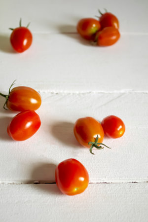 Red cherry tomatoes on a white table. fresh small tomatoes. Cherry tomato - a few pieces are on the table.の写真素材