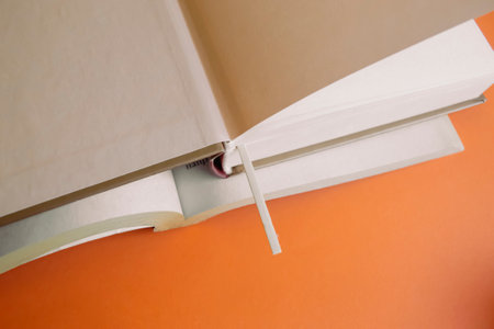Open books with bookmark on an orange background. There is a wooden bookmark in the book.の写真素材