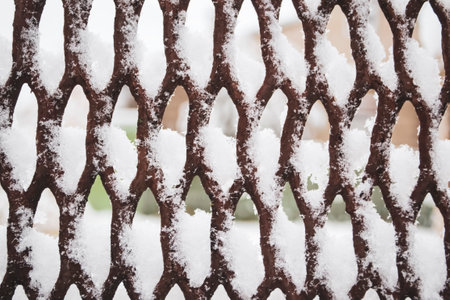 Metal grating in the snow. Abstraction - lattice, snow. The grille is covered with white snow - winter.の写真素材