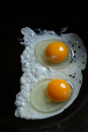 Scrambled eggs in a black pan. English breakfast - fried eggs with two eggs. fried eggs.の写真素材