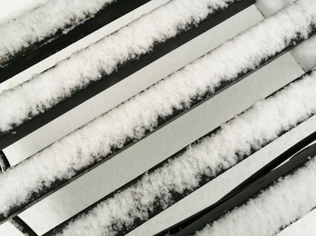 The seat of the bench is covered with snow. Abstraction - wooden planks in the snow close-up. A shop on the street. Snow bench.の写真素材