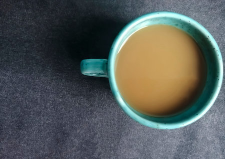 Cup of coffee on a dark background. Shot from above - coffee with milk on a black tablecloth.の写真素材